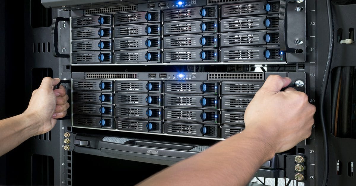 Two hands grab hold on each side of a segment within a data server rack with sixteen components inside the segment.